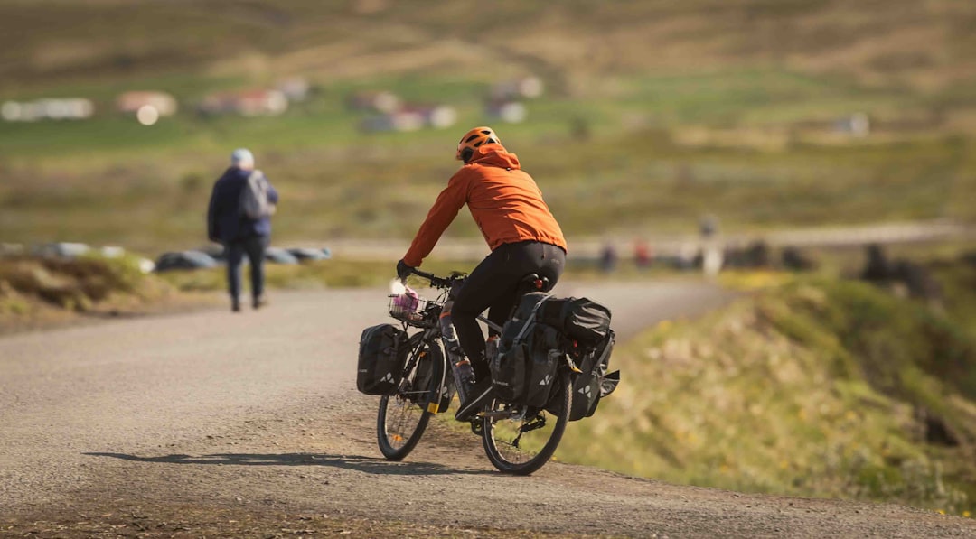 A person biking on a rural road with rolling hills in the background, highlighting sustainable travel through cycling.