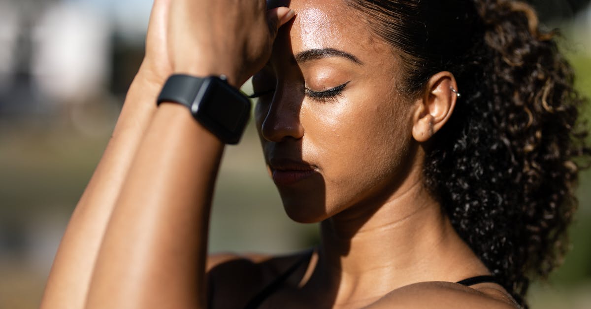 A person with curly hair is holding a smartwatch, possibly engaging with a mental health app, during an outdoor activity.