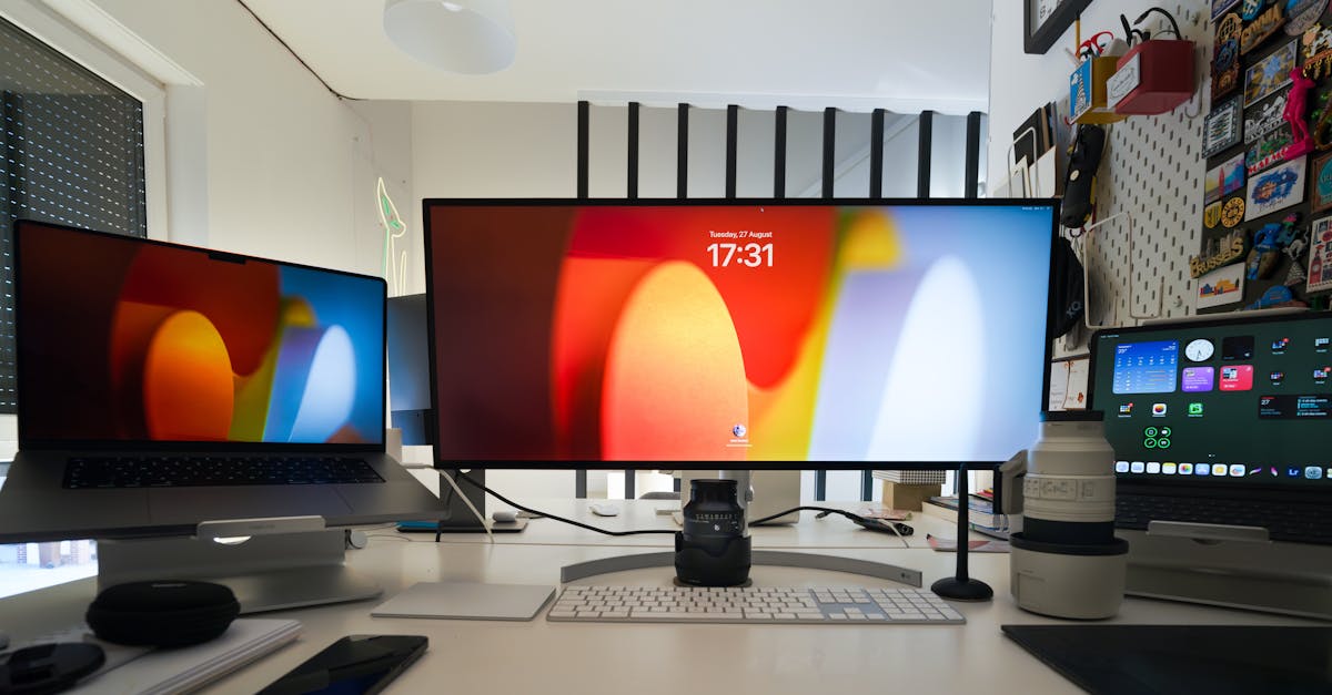 A workspace with two monitors, a laptop, a white keyboard, and various electronic devices on a white desk.