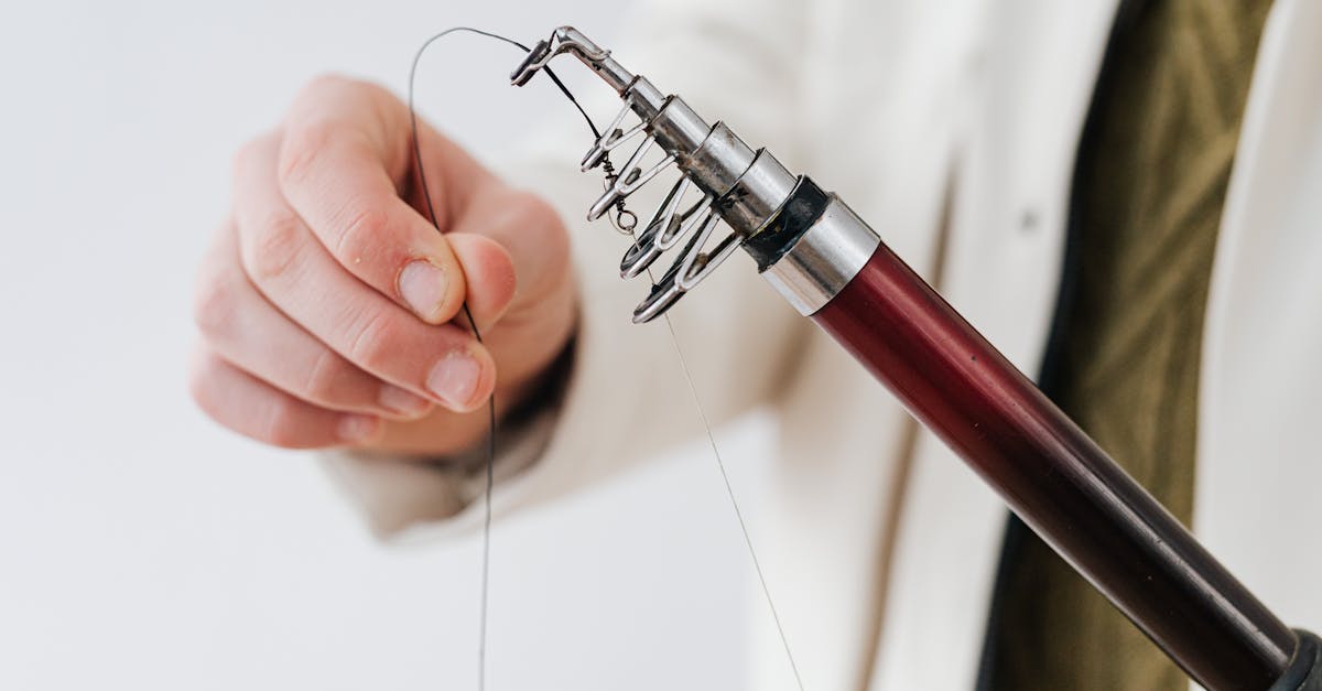 A hand holding a fishing hook with a blurred background, illustrating the Fisherman Core aesthetic.