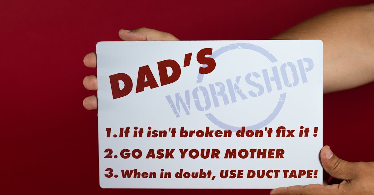 Hand holding a workshop sign with tips: 'If it isn’t broken don’t fix it!', 'Go ask your mother', and 'Use duct tape when in doubt'.