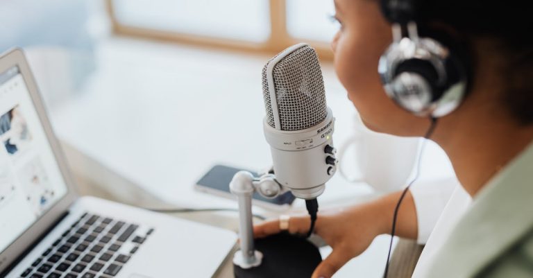 Close-up of a microphone and laptop used for remote communication and virtual meetings, in a well-lit workspace.