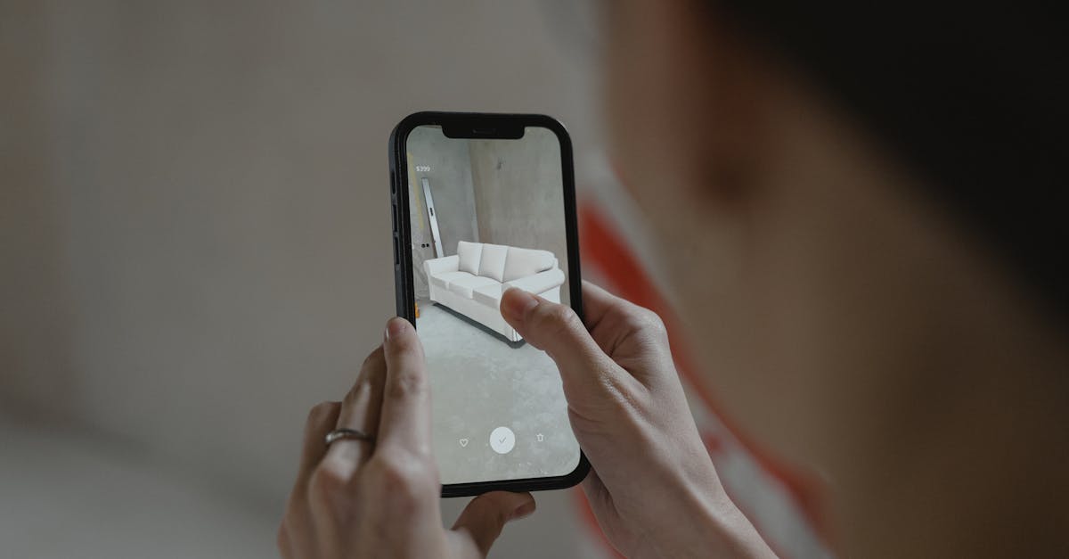 A person holding a smartphone, using augmented reality to view and capture a virtual overlay of a modern sofa inside a room.